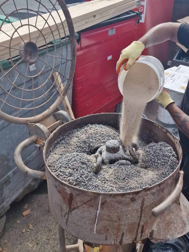 Pouring resin materials into a mixer for resin driveway-style resin bound surface installation.