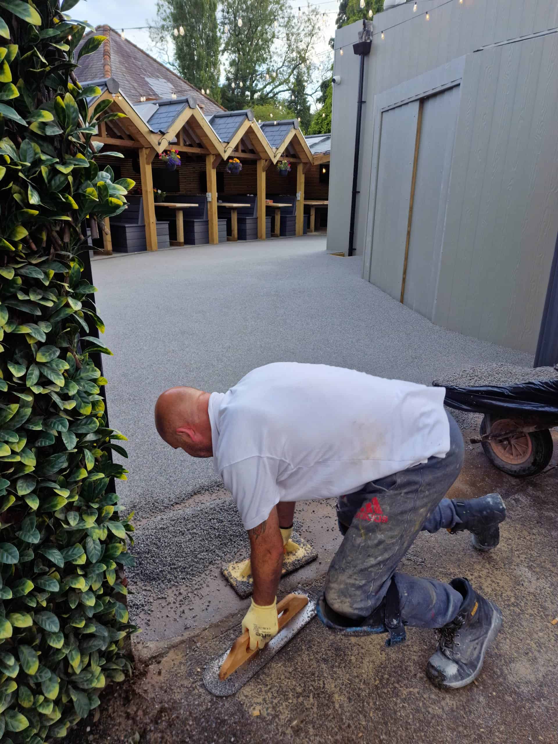 Final finishing touches on resin driveway installation at West Midlands pub beer garden with crisp edge detailing