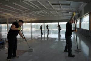 Applying UV-stable top coat to self levelling epoxy resin floor using a roller.