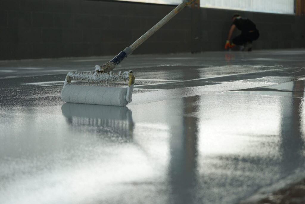 Applying UV-stable gloss seal over decorative flakes on self levelling epoxy resin floor in West Bromwich commercial space