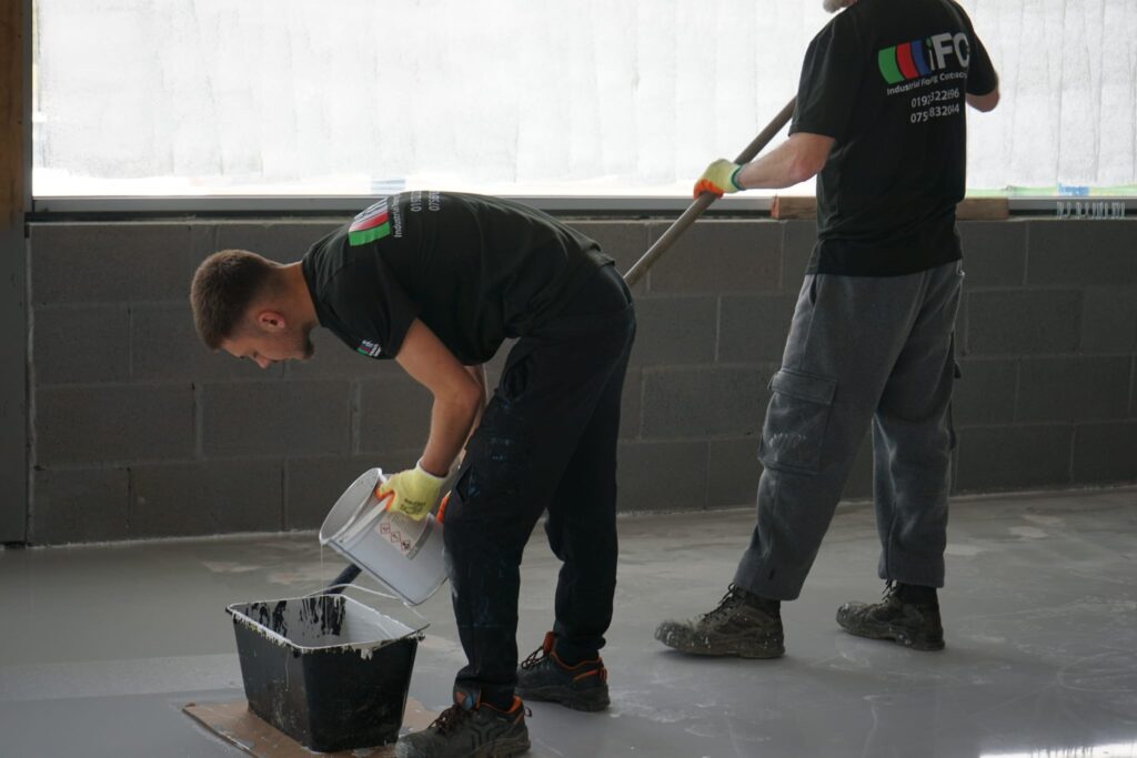 Team member preparing self levelling epoxy resin mixture in bucket.