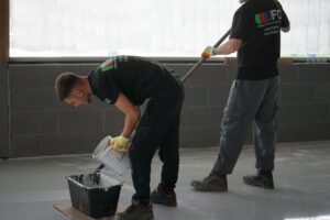 Team member preparing self levelling epoxy resin mixture in bucket.