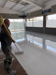 Lee Taylor MD applying UV-stable top coat with roller on self levelling epoxy resin floor.