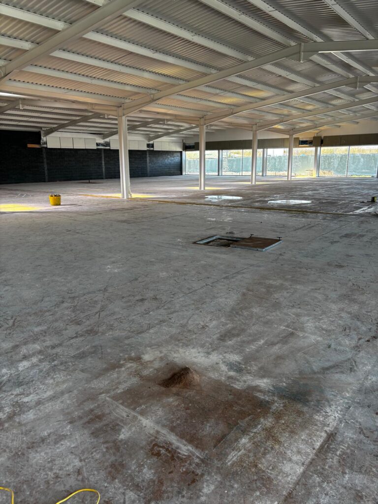 Supermarket floor showing manholes and uneven sections before self levelling epoxy resin installation in West Bromwich