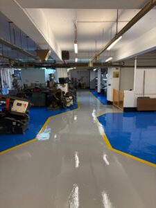Finished high build epoxy resin flooring in the West Midlands showing blue and grey zones with yellow lines.